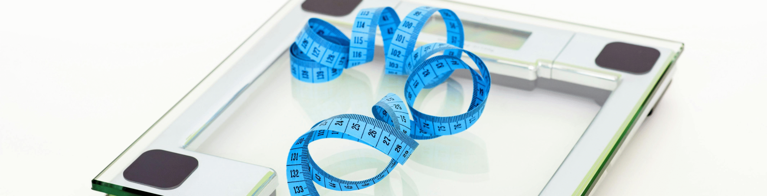 Glass digital bathroom scale with a blue measuring tape coiled on top
